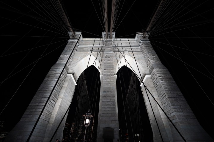 One of the towers on the Brooklyn bridge, where the cables go to support the bridge. The picture is black and white, and taken at night.